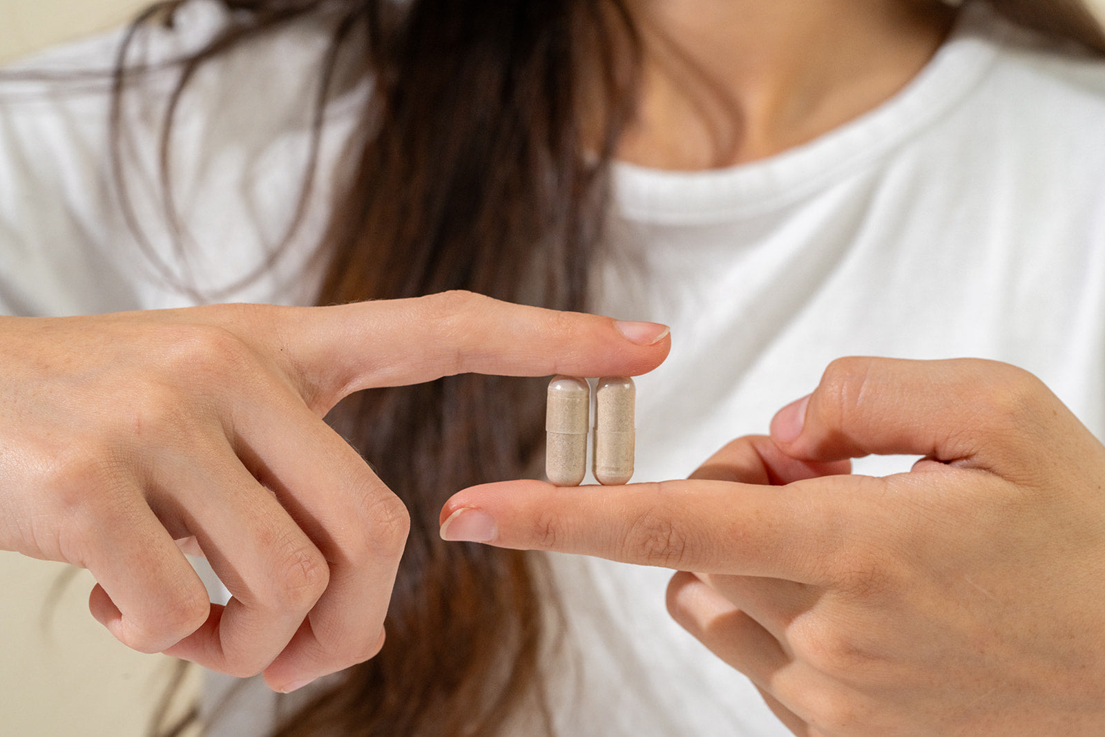 Two of The Baseline pills being held up by two fingers